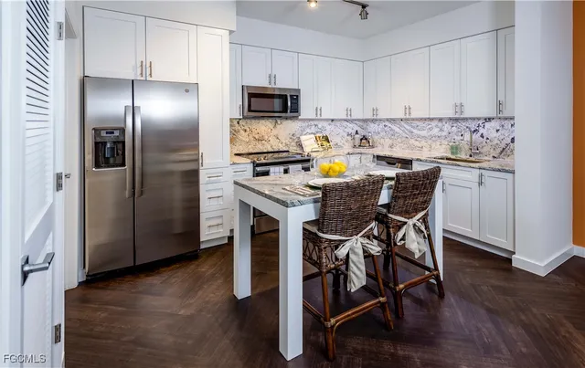 a kitchen with stainless steel appliances a table chairs refrigerator and microwave