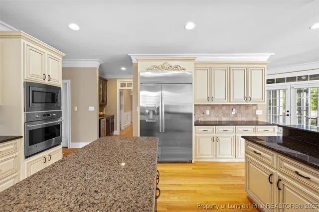 a large kitchen with stainless steel appliances granite countertop a refrigerator and a stove top oven