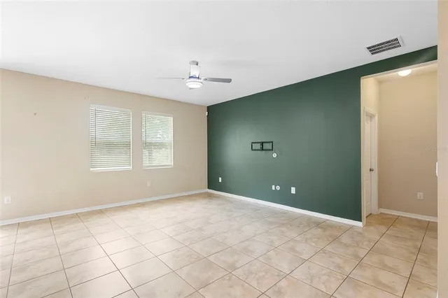 a view of an empty room with window and chandelier fan