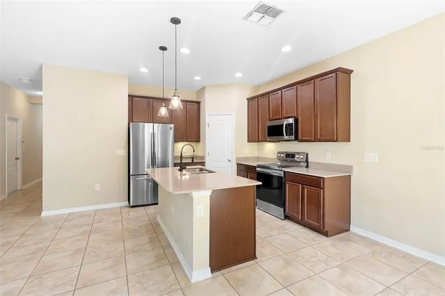 a kitchen with stainless steel appliances granite countertop a refrigerator a stove a sink and a microwave