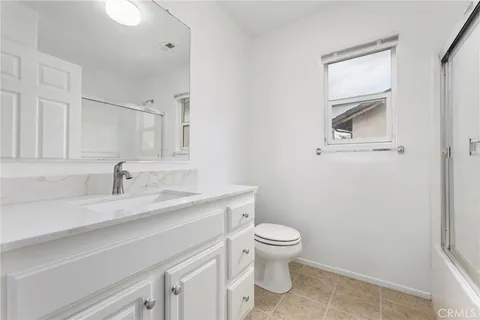 a bathroom with a granite countertop sink toilet and mirror