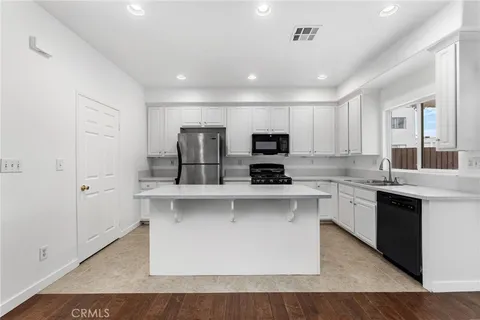 a large white kitchen with stainless steel appliances granite countertop a stove and a sink