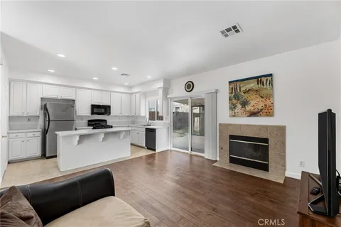 a living room with stainless steel appliances furniture a fireplace a flat screen tv and view kitchen