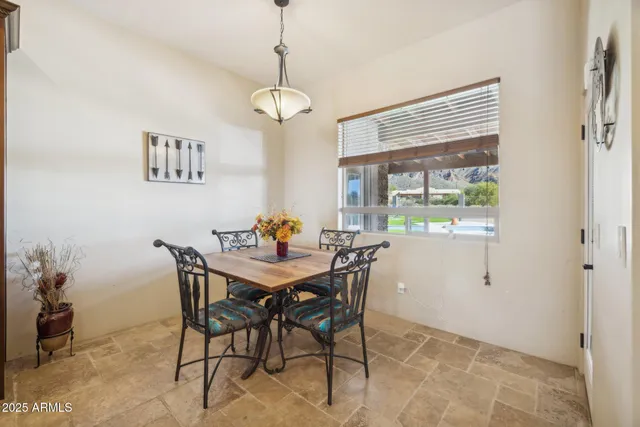 a kitchen with stainless steel appliances granite countertop a refrigerator a stove a sink a dining table and chairs with wooden floor