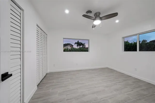 a view of a room with wooden floor fan and windows