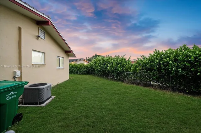 a view of a backyard with grass and a large tree