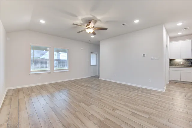 a view of an empty room with a window and wooden floor