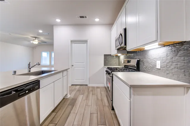 a kitchen with stainless steel appliances granite countertop a sink a stove and a wooden floors