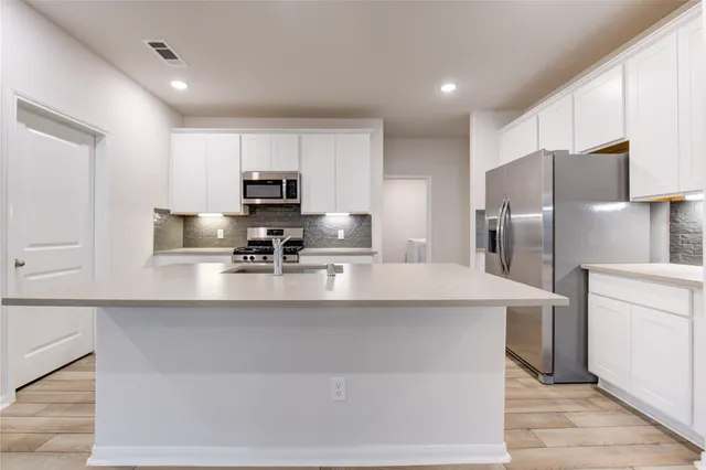 a kitchen with stainless steel appliances a refrigerator sink and microwave