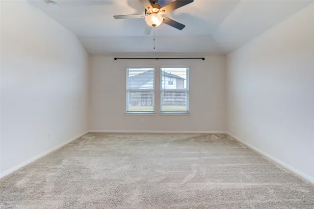 an empty room with chandelier fan and windows