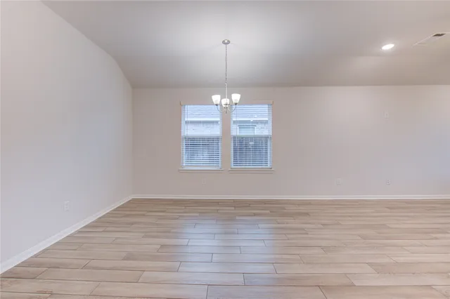 a view of empty room with wooden floor and window