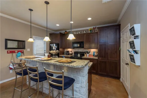 a kitchen with stainless steel appliances granite countertop a refrigerator a sink dishwasher a dining table and chairs with wooden floor