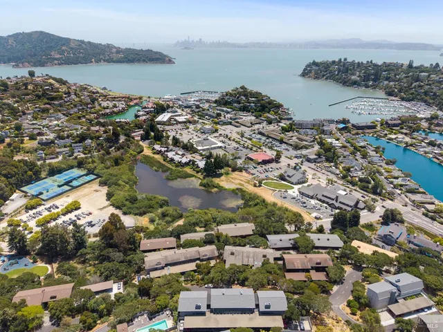 an aerial view of ocean and residential houses with outdoor space
