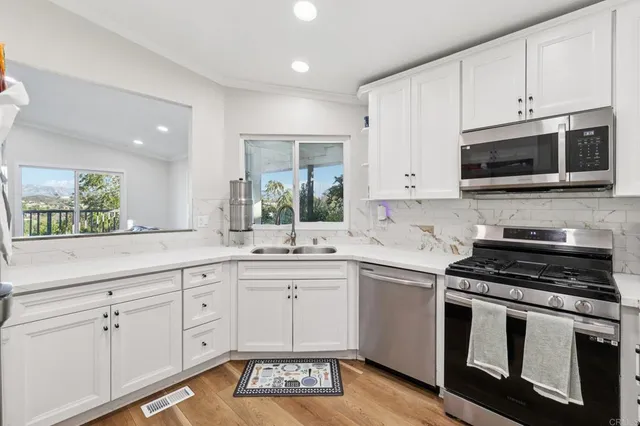 a kitchen with stainless steel appliances kitchen island granite countertop a refrigerator a stove a sink a dining table and chairs with wooden floor