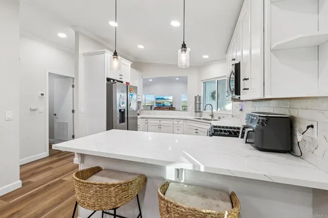 a kitchen with stainless steel appliances kitchen island granite countertop a refrigerator sink and white cabinets