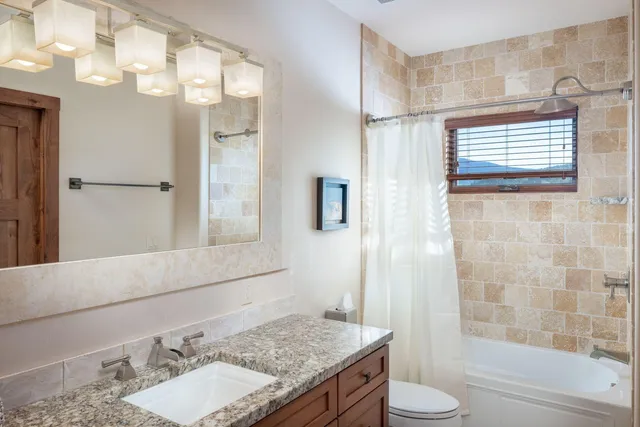 a bathroom with a granite countertop sink toilet and shower