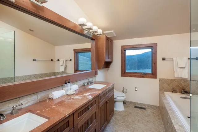 a spacious bathroom with a granite countertop sink a toilet a mirror and shower