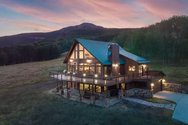 a view of a big house with a big yard and large trees