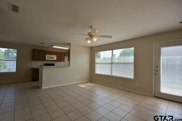 an empty room with windows and fan