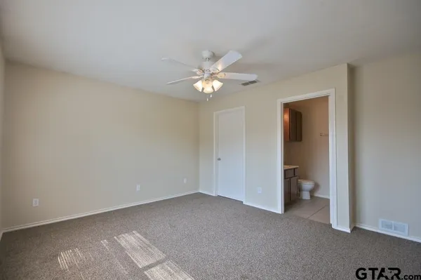 an empty room with a chandelier fan and windows