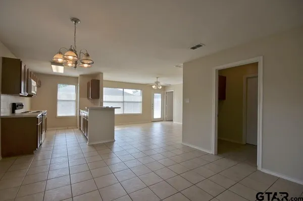 a view of an empty room with a chandelier fan