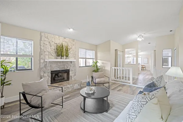 a living room with furniture a fireplace and potted plants with wooden floor
