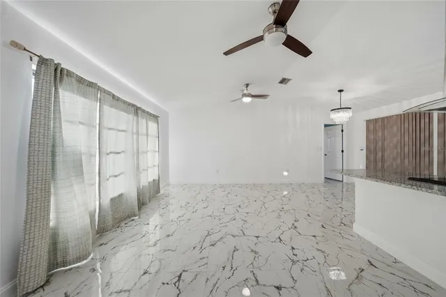 an empty room with a ceiling fan and window