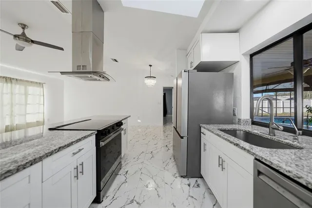 a kitchen with stainless steel appliances granite countertop a sink a stove and a refrigerator