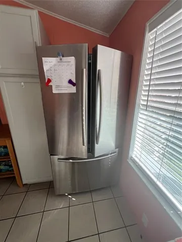 a view of a refrigerator in kitchen and an empty room