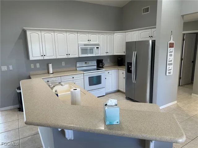 a kitchen with stainless steel appliances granite countertop a refrigerator a sink a stove a washer and white cabinets