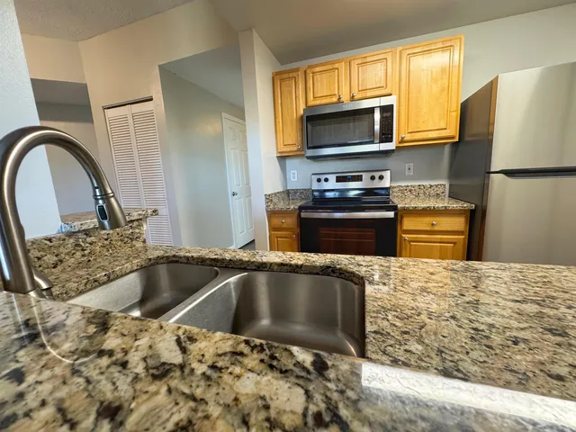 a kitchen with granite countertop a sink and a stove top oven