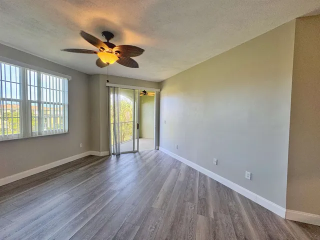 a view of an empty room with window and wooden floor