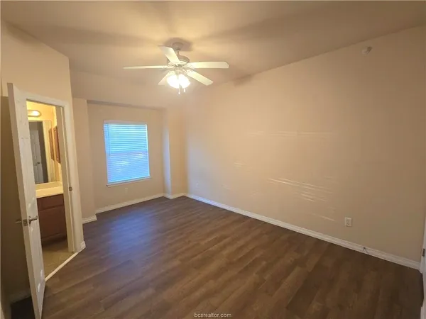 an empty room with wooden floor fan and windows