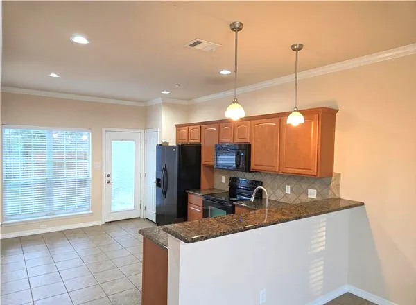 a kitchen with stainless steel appliances granite countertop a sink a refrigerator and a wooden floor
