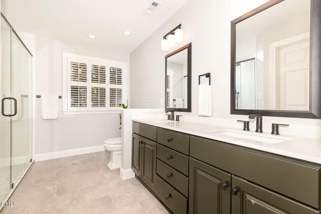 a bathroom with a double vanity sink a toilet and a mirror