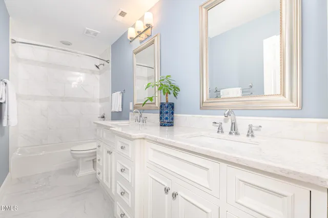 a bathroom with a double vanity sink toilet and shower