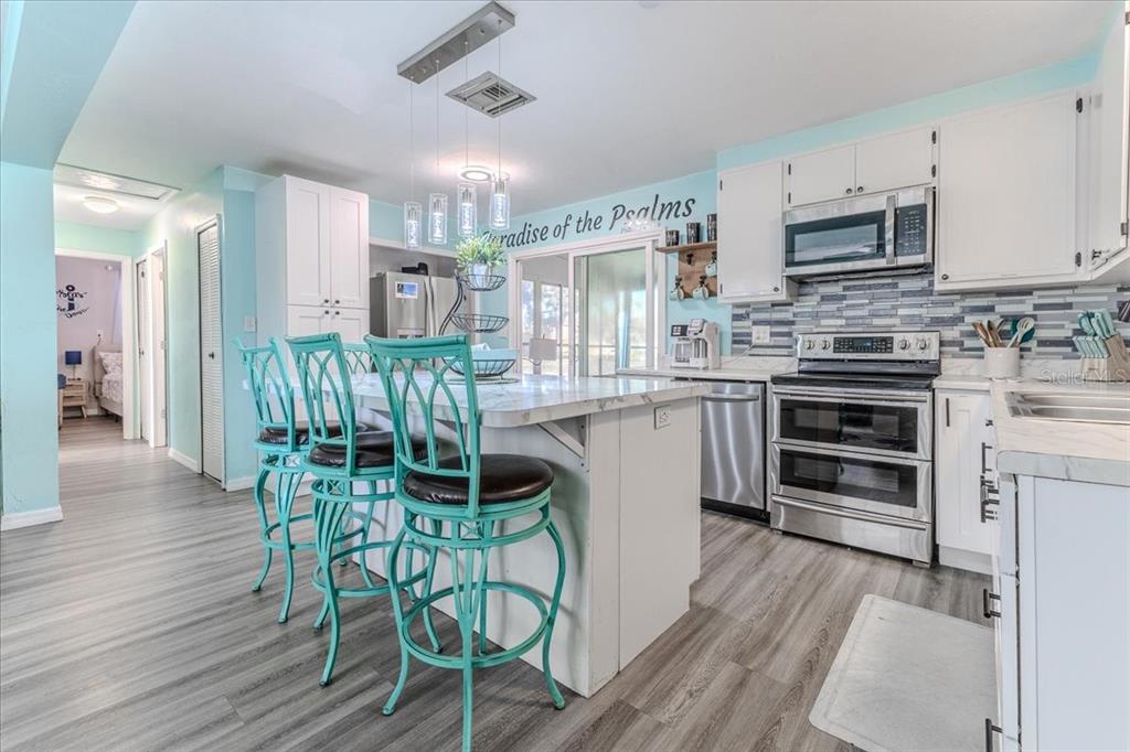 5261 Circle Drive Weeki Wachee, FL 34607 - Photo 23 of 49 a kitchen with stainless steel appliances a stove a sink dishwasher a dining table and chairs with wooden floor