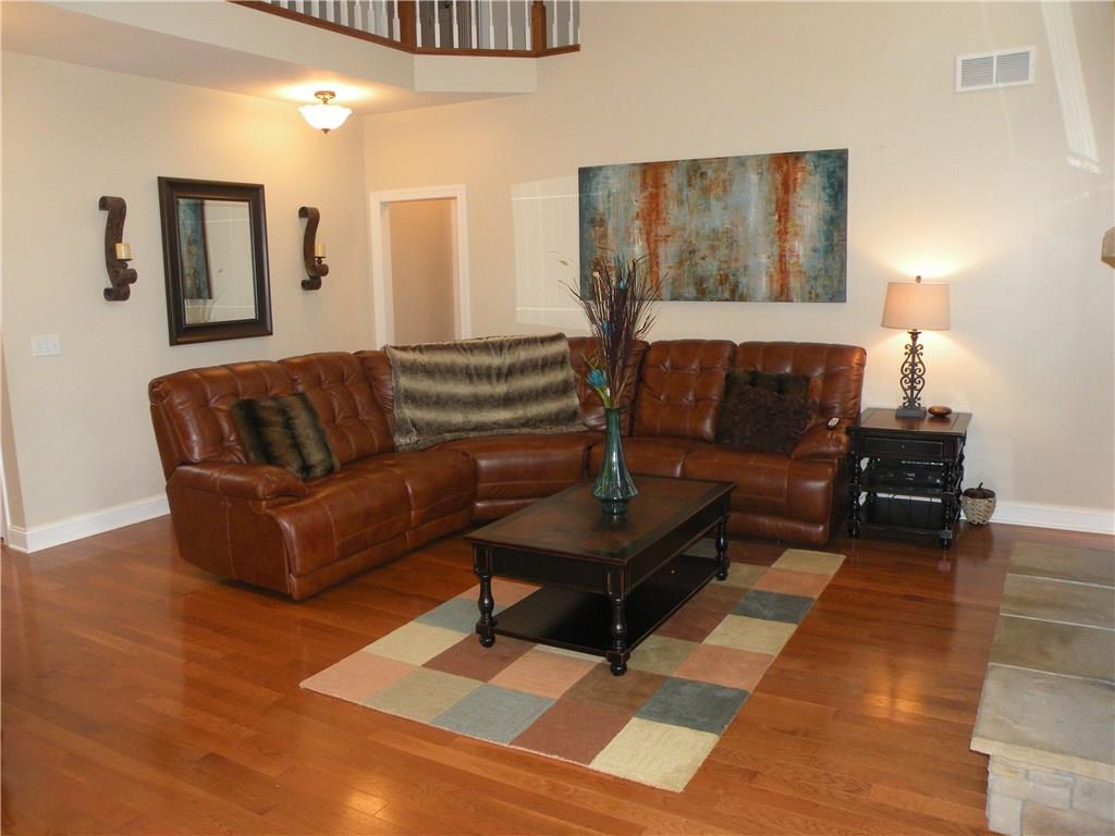 1145 Mohawk Road McDonald, PA 15057 - Photo 12 of 24 1145 Mohawk Road Sun-drenched Family Room - Features a floor to ceiling stone hearth fireplace, neutral wall tone, large windows, hardwood flooring