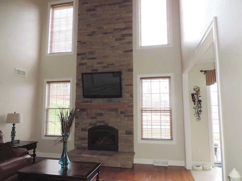 1145 Mohawk Road McDonald, PA 15057 - Photo 13 of 24 1145 Mohawk Road Sun-drenched Family Room - Features a floor to ceiling stone hearth fireplace, neutral wall tone, large windows, hardwood flooring