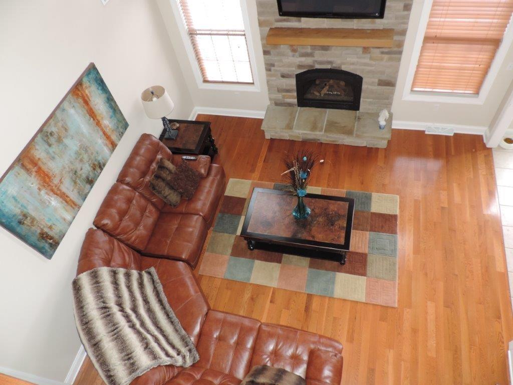 1145 Mohawk Road McDonald, PA 15057 - Photo 14 of 24 1145 Mohawk Road Sun-drenched Family Room - Features a floor to ceiling stone hearth fireplace, neutral wall tone, large windows, hardwood flooring