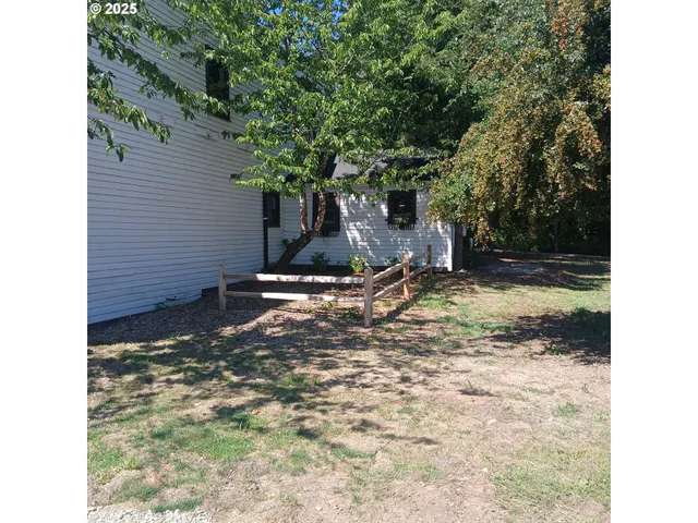 a view of brick house with backyard and chairs