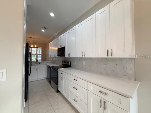 a kitchen with white cabinets and sink