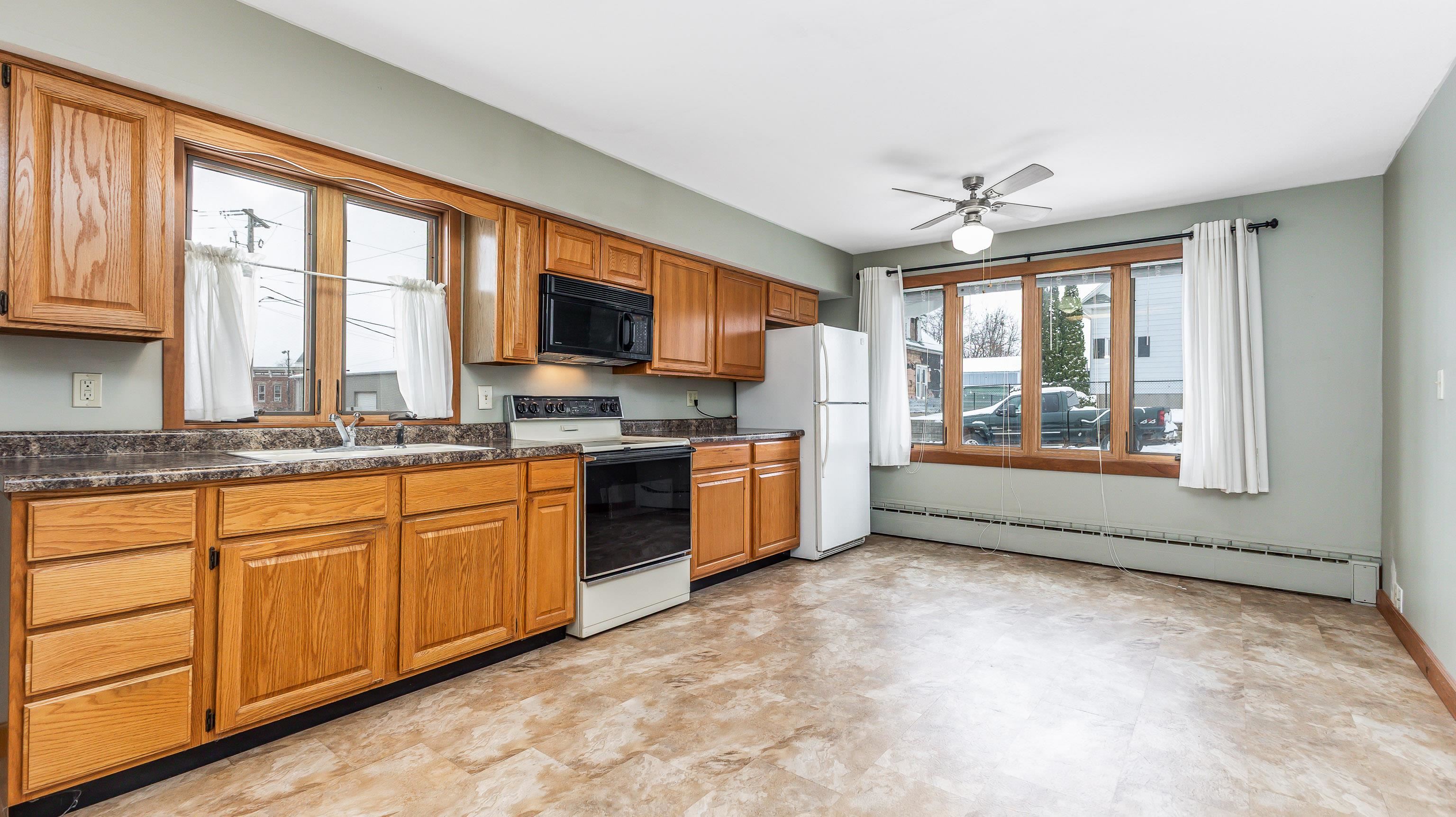 319 East Catlin Street Elizabeth, IL 61028 - Photo 7 of 26 a open kitchen with granite countertop a stove top oven a sink dishwasher a dining table and chairs with wooden floor