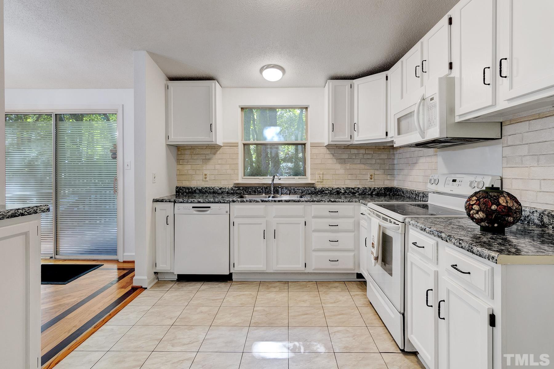 7317 Shellburne Drive Raleigh, NC 27612 - Photo 11 of 28 a kitchen with granite countertop white cabinets and white appliances