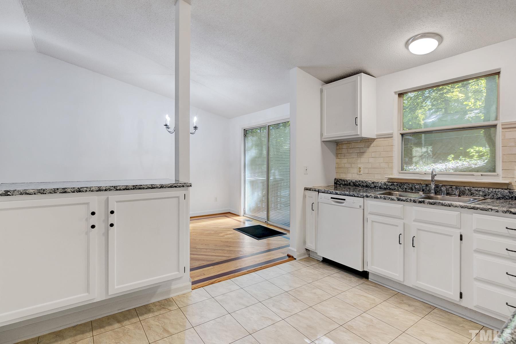 7317 Shellburne Drive Raleigh, NC 27612 - Photo 8 of 28 a kitchen with granite countertop white cabinets and window