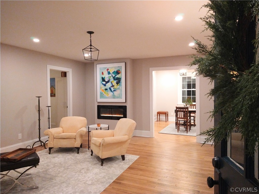 Living room featuring new modern lighting, new modern fireplace, newly finished flooring.