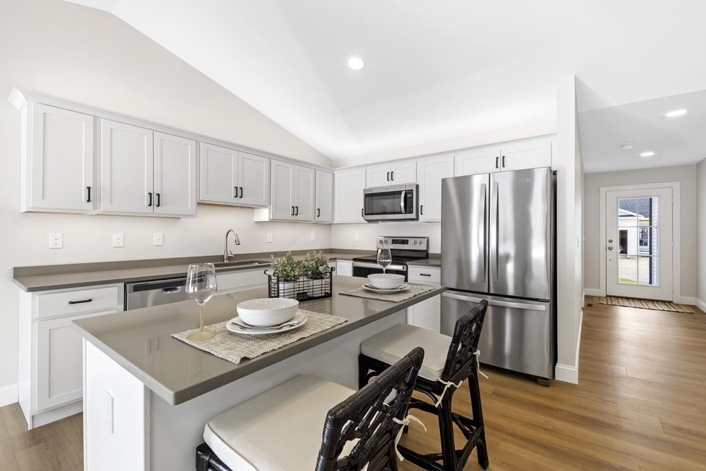 139 Harvard Street, Unit 10 Fitchburg, MA 01420 - Photo 2 of 11 a kitchen with a refrigerator a stove a sink and white cabinets with wooden floor