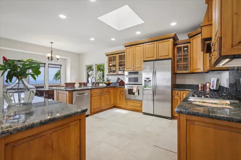 a kitchen with stainless steel appliances granite countertop a refrigerator a stove and a sink with wooden floor