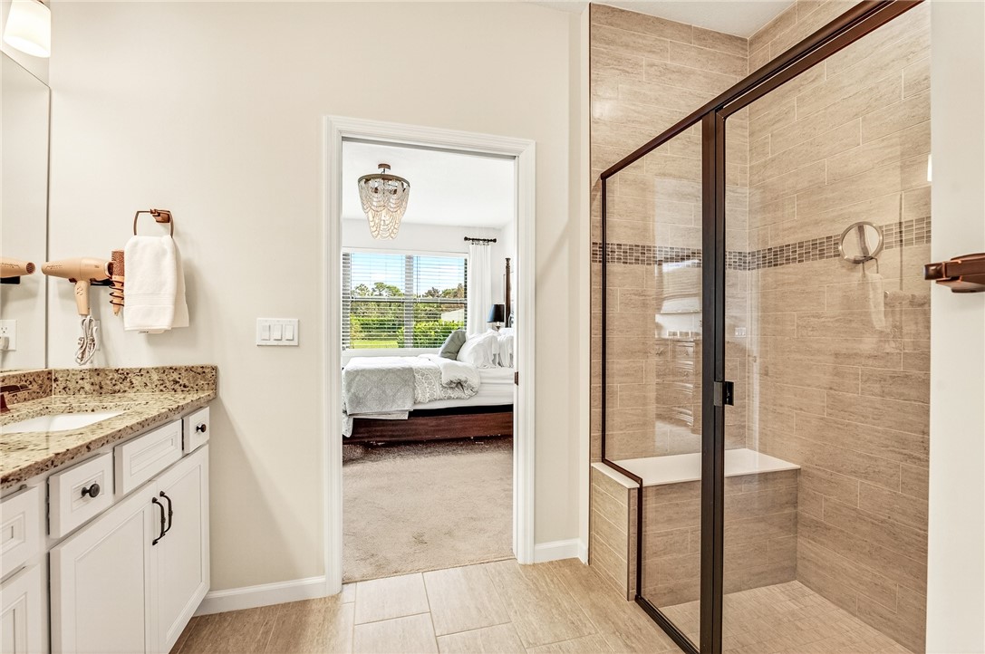 5191 Unity Square Vero Beach, FL 32967 - Photo 22 of 36 a en suite bathroom with a granite countertop sink a mirror and shower