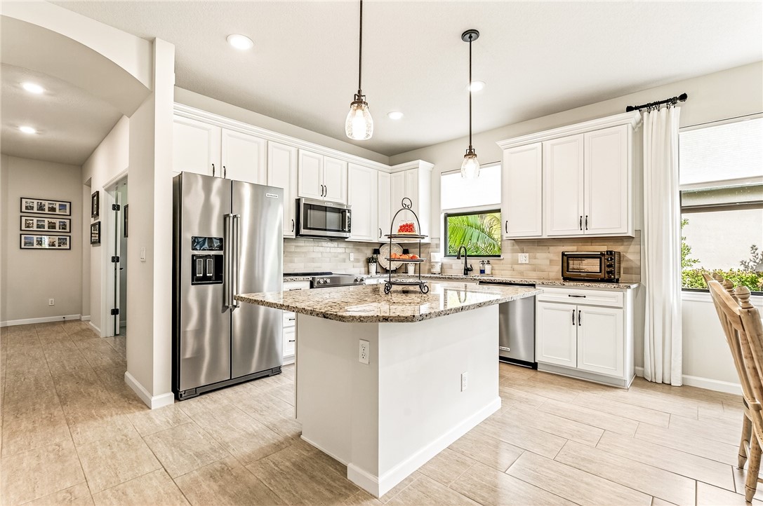 5191 Unity Square Vero Beach, FL 32967 - Photo 8 of 36 a kitchen with stainless steel appliances kitchen island granite countertop a refrigerator a sink dishwasher a oven with white cabinets and wooden floor